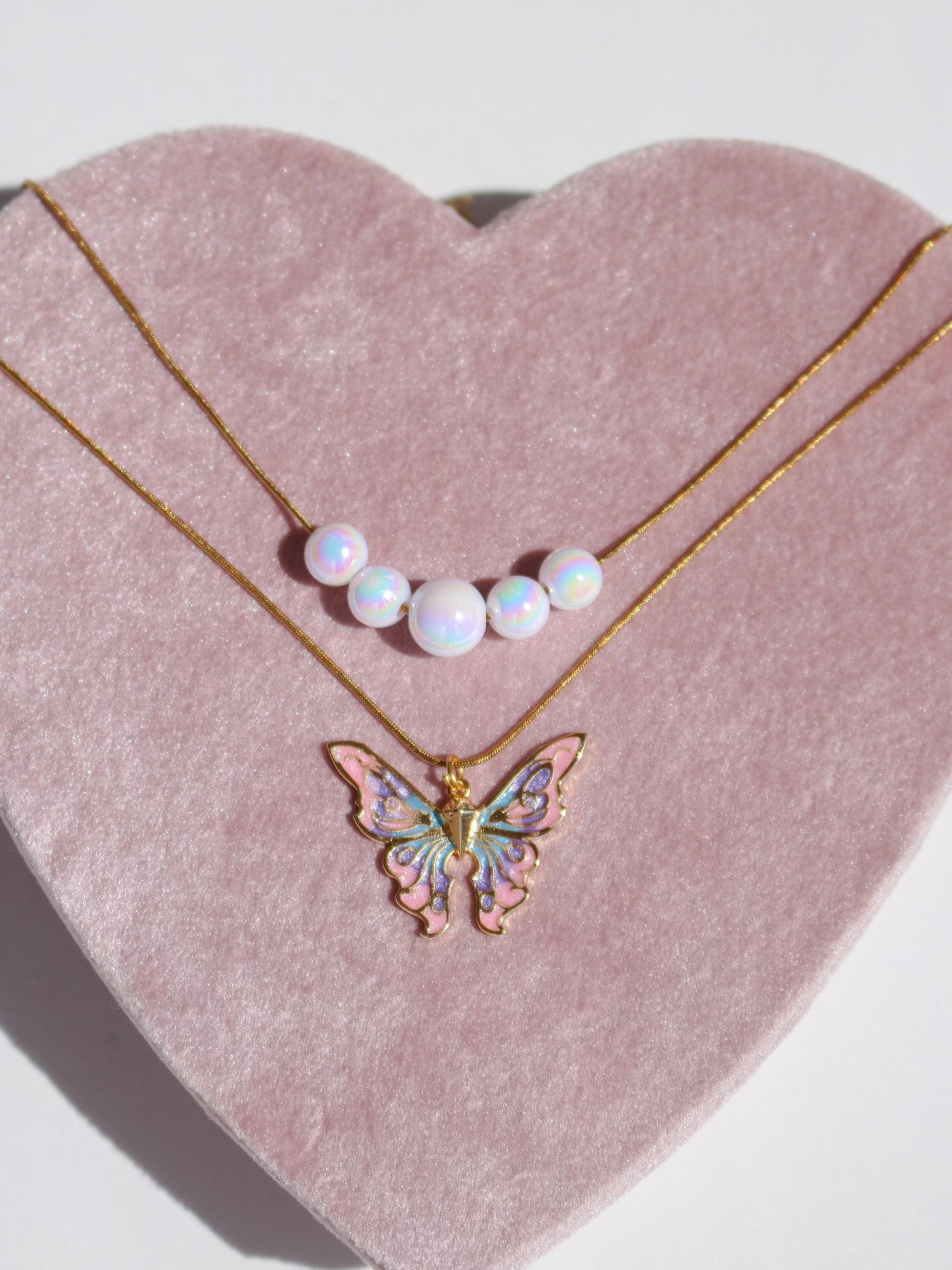 Shimmer with the Elina Butterfly and Mermaid Holographic Pearl Necklace Set. Features iridescent charms, luminous pearls, and a magical whimsical style. Shop now!