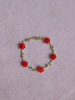 Belle La Vie En Rose Bracelet with red rose decorations on a light purple background