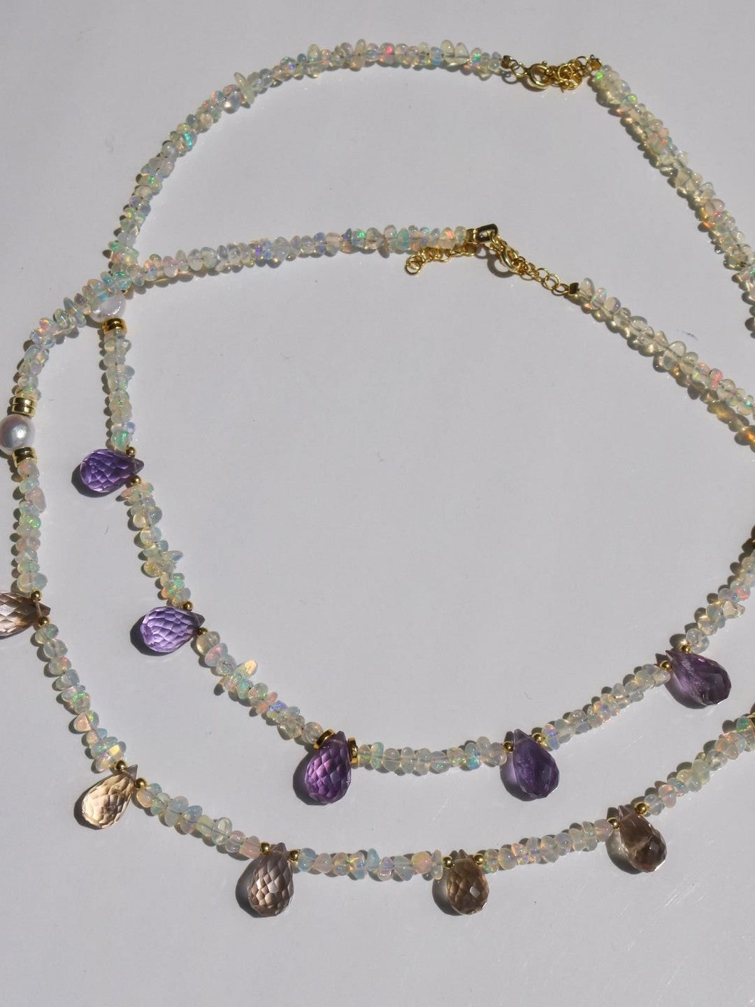 A sterling silver necklace with real opal stone design, featuring multiple opal pendants and adorned with gold-colored accents.