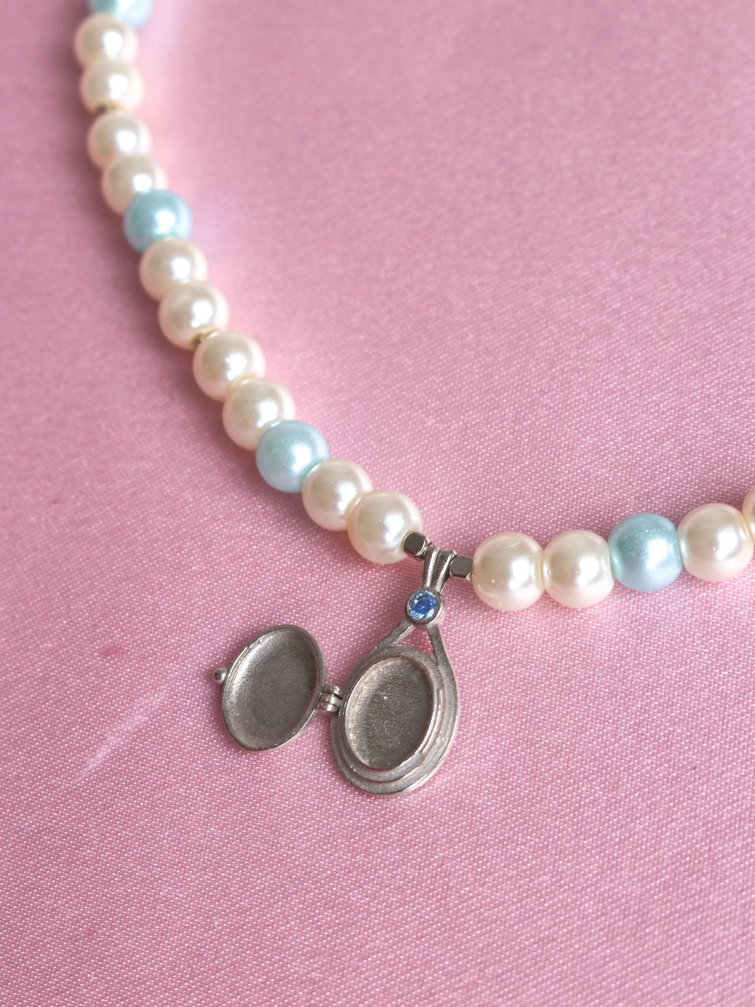 H2O Just Add Water Pearl Design Necklace necklace with a silver-colored clasp, laid out on a pink background.