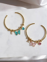 Two gold-colored friendship bracelets with charms, displayed on a white surface.