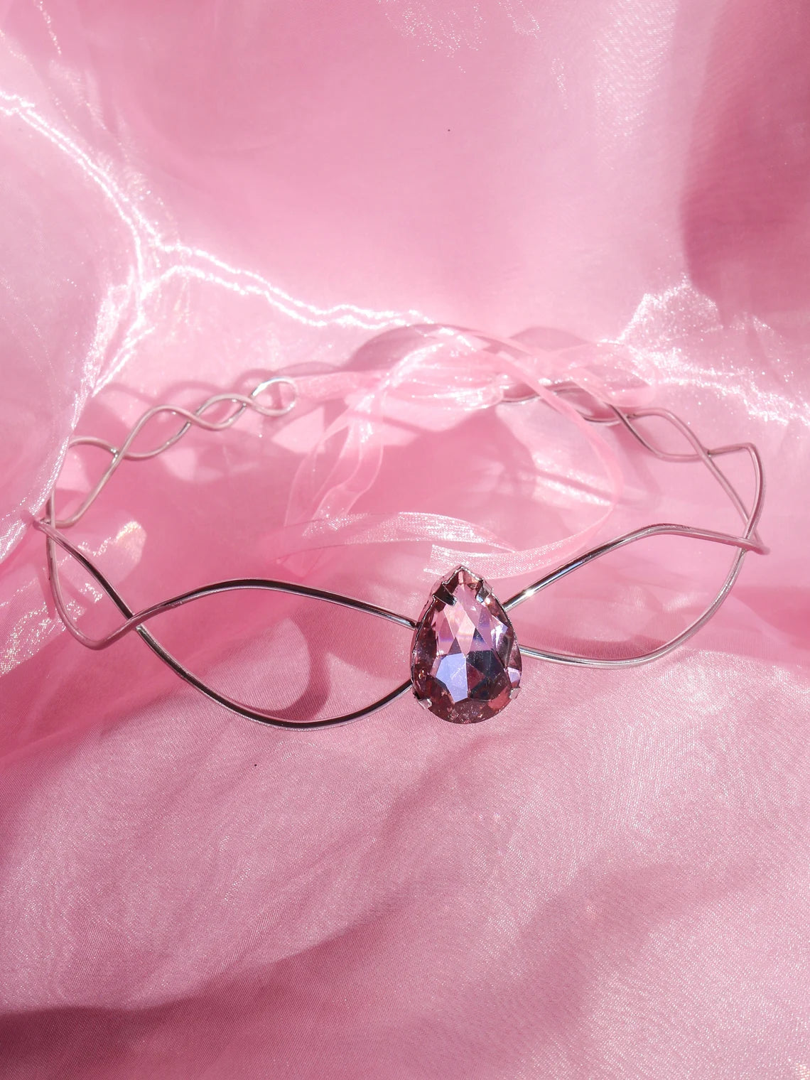 Swan Princess Odette Pink Stone Tiara, with a pink central stone, displayed on a pink fabric background.